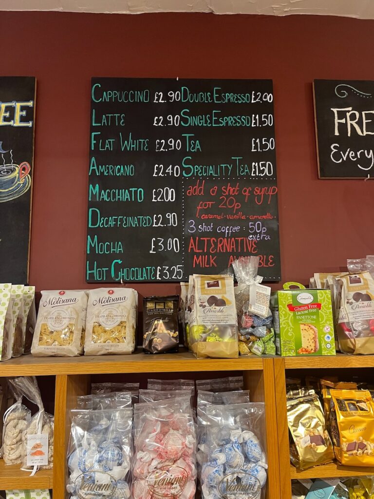 A board showing Amaretto Deli's take-away coffee prices